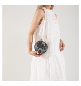 Macro detail of round sequin evening bag featuring gold chain and metallic handle