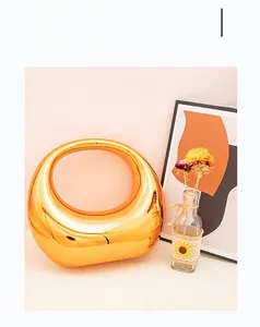 Détail d'un vase ovale moderne en céramique dorée creuse avec une finition miroir galvanisée