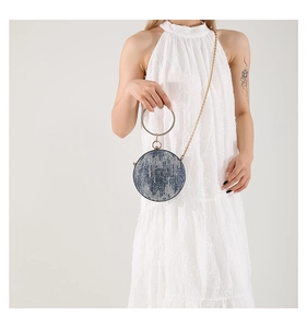 Close-up of a blue denim round evening bag with a gold rhinestone ring handle and chain