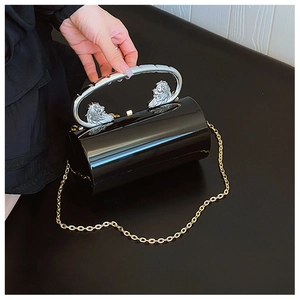 Detail of cylindrical acrylic evening bag with lion head handles and gold chain strap