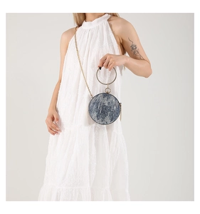 Detail of blue denim sphere bag with golden ring handle and elegant metal chain strap