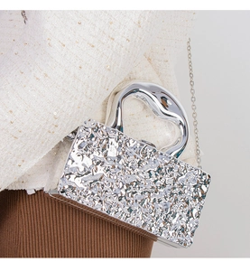 Silver mirror bag with lava texture and irregular handle worn over a tweed jacket