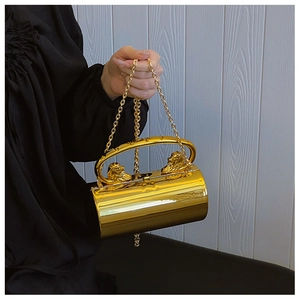 Detail of gold cylindrical acrylic evening bag featuring ornate lion head sculptures