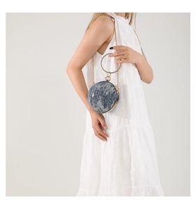 Spherical denim texture mini clutch bag with crystal handle held by woman in lace dress