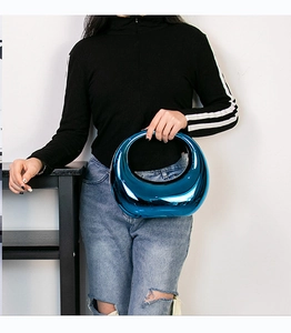 Détail de la pochette bleu métallisé avec poignée ovale évidée et finition miroir brillante