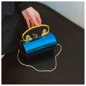 Detail of teal cylindrical clutch with lion head gold handle and metallic chain strap
