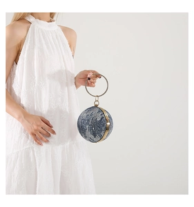 Detail view of denim texture spherical clutch bag with gold ring handle and embroidery