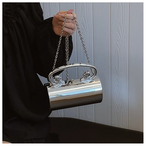 Detail of silver cylindrical acrylic bag featuring lion head handles and chain strap