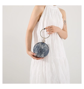 Close-up of a navy spherical evening bag with metallic handle and textured finish