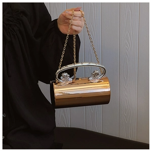 Detail of cylindrical metal evening bag with lion head relief handle and chain strap