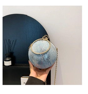 Detail of light blue spherical evening bag with golden ring handle and vertical sequins
