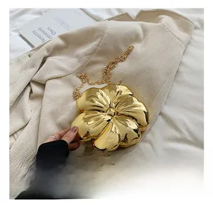 Detailed close-up of golden metallic flower-shaped evening clutch bag with chain strap