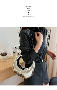 Detalle del bolso de media luna plateado metálico con cadena en ambiente moderno