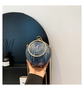 Detail of creative sphere handbag featuring blue denim, silver sequins and gold handle