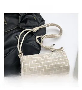 Détail d'un sac boston en nylon beige à carreaux avec logo fashion et bandoulière nouée