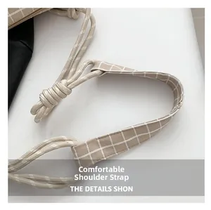 Détail de la bandoulière en nylon à carreaux avec un nœud décoratif en coton tissé