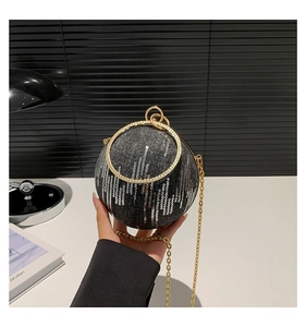 Detailed view of spherical evening bag with silver sequins and golden ring handle