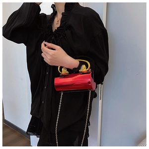 Detail of red metallic evening bag with golden lion head accents and elegant chain strap