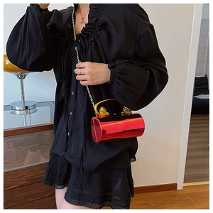 Chic red cylindrical acrylic handbag featuring a golden lion head and chain strap