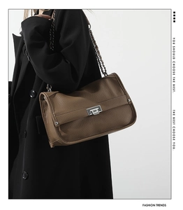 Detail of a brown lychee pattern leather messenger bag with silver square metal clasp