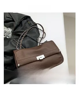 Detailed close-up of brown litchi pattern leather bag with silver metal swivel lock