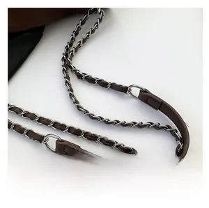 Detail of brown leather interwoven with silver metal chain strap on messenger bag