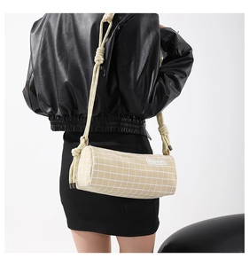 Détail du sac cylindrique à carreaux avec bandoulière en corde sur veste en cuir