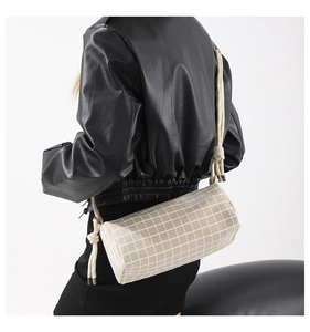 Détail du sac cylindre en nylon beige à carreaux avec bandoulière en corde à nœuds