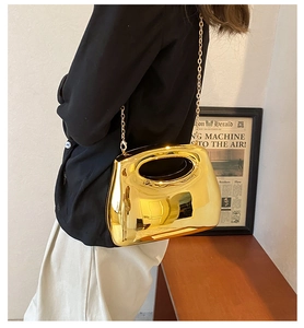 Close-up of golden mirrored acrylic evening clutch with liquid metal finish and chain strap