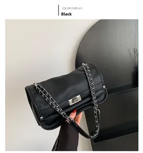 Close-up of black lychee grain leather messenger bag with silver twist lock and rivets