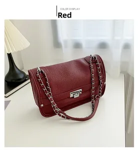 Detail of red pebbled leather messenger bag with silver twist lock and chain strap