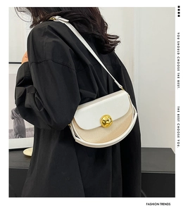 Detailed side view of minimalist crescent bag with woven texture and gold ball clasp
