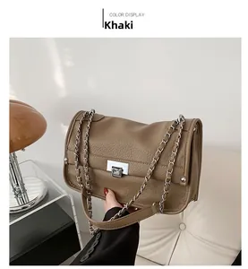 Detail of khaki pebbled leather messenger bag featuring silver metal buckle and chain strap