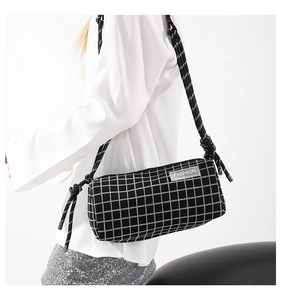 Détail du sac bandoulière cylindre en nylon à carreaux avec bandoulière tissée