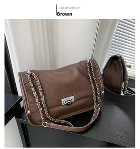Detail of brown lychee grain leather crossbody bag with silver clasp and chain strap