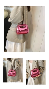 Detail view of fuchsia metallic clutch with golden chain strap and hollow handle