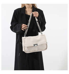 Macro detail of creamy white lychee grain leather texture and metallic twist lock closure
