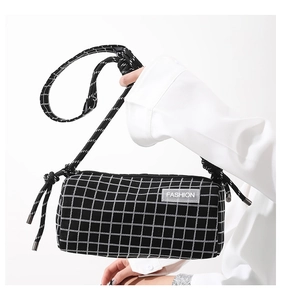 Détail du sac bandoulière en nylon à carreaux avec sangle nouée et étiquette