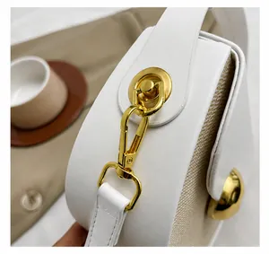 Close-up of golden metal hooks and hardware on the white woven leather handbag