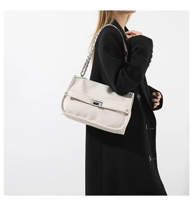 Detail of cream pebbled leather messenger bag with gold chain strap and turn-lock closure