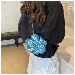Detail showing metallic blue flower-shaped handbag with a gold chain strap on a model