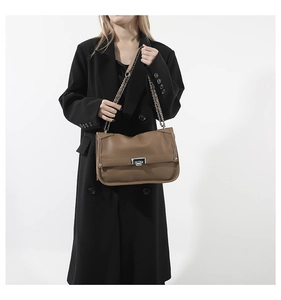 Detail of brown litchi leather messenger bag with silver twist lock and chain strap