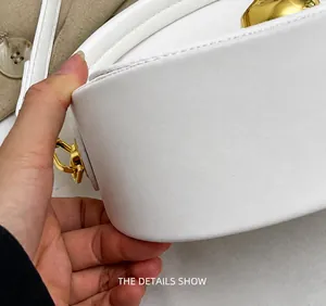 Detailed close-up of white leather handbag stitching and gold D-ring hardware details