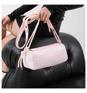 Détail du sac cylindrique à carreaux roses avec poignée en corde nouée et zip argenté