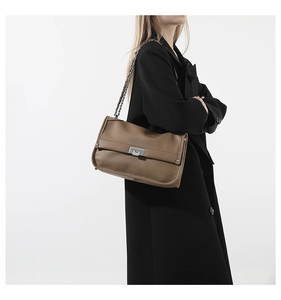 Detail of dark coffee leather messenger bag with silver metal clasp and chain strap