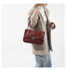 Detailed view of dark red lychee grain leather crossbody bag with silver chain and metal clasp