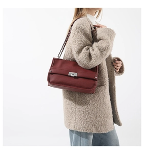Detail shot of a burgundy pebbled leather messenger bag with silver metallic clasp