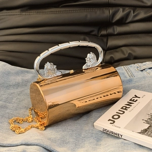Golden cylindrical acrylic clutch bag with lion head handles and chain strap