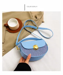 Detailed view of light blue semicircular bag with gold buckle on a beige blazer