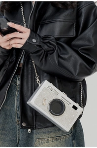 Dettaglio di una borsa a tracolla di lusso a forma di fotocamera con strass e catena